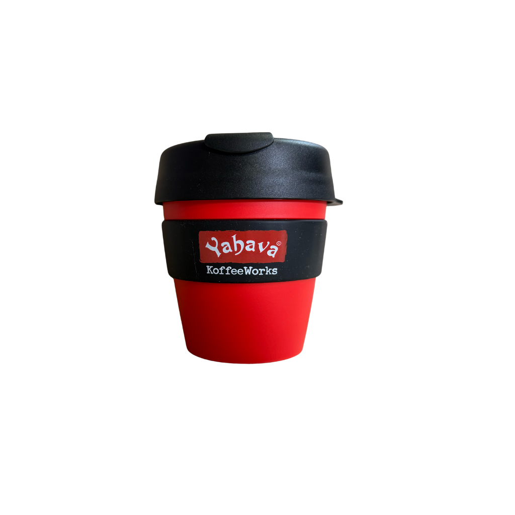 A reusable coffee cup with a red body, black lid, and black band around the middle featuring the 'Yahava KoffeeWorks' logo, shown on a plain white background.