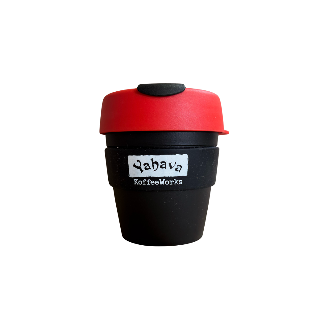 A reusable coffee cup with a black body, a red lid, and a black silicone band around the middle. The band has a white label that reads 'Yahava KoffeeWorks'.