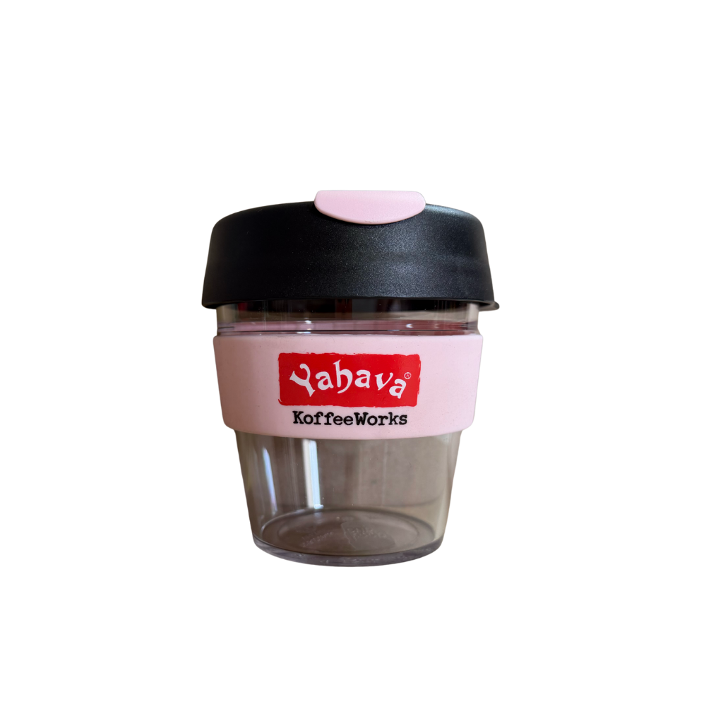 A reusable coffee cup with a black lid, pink silicone sleeve, and clear plastic body, featuring the 'Yahava KoffeeWorks' logo on the sleeve.