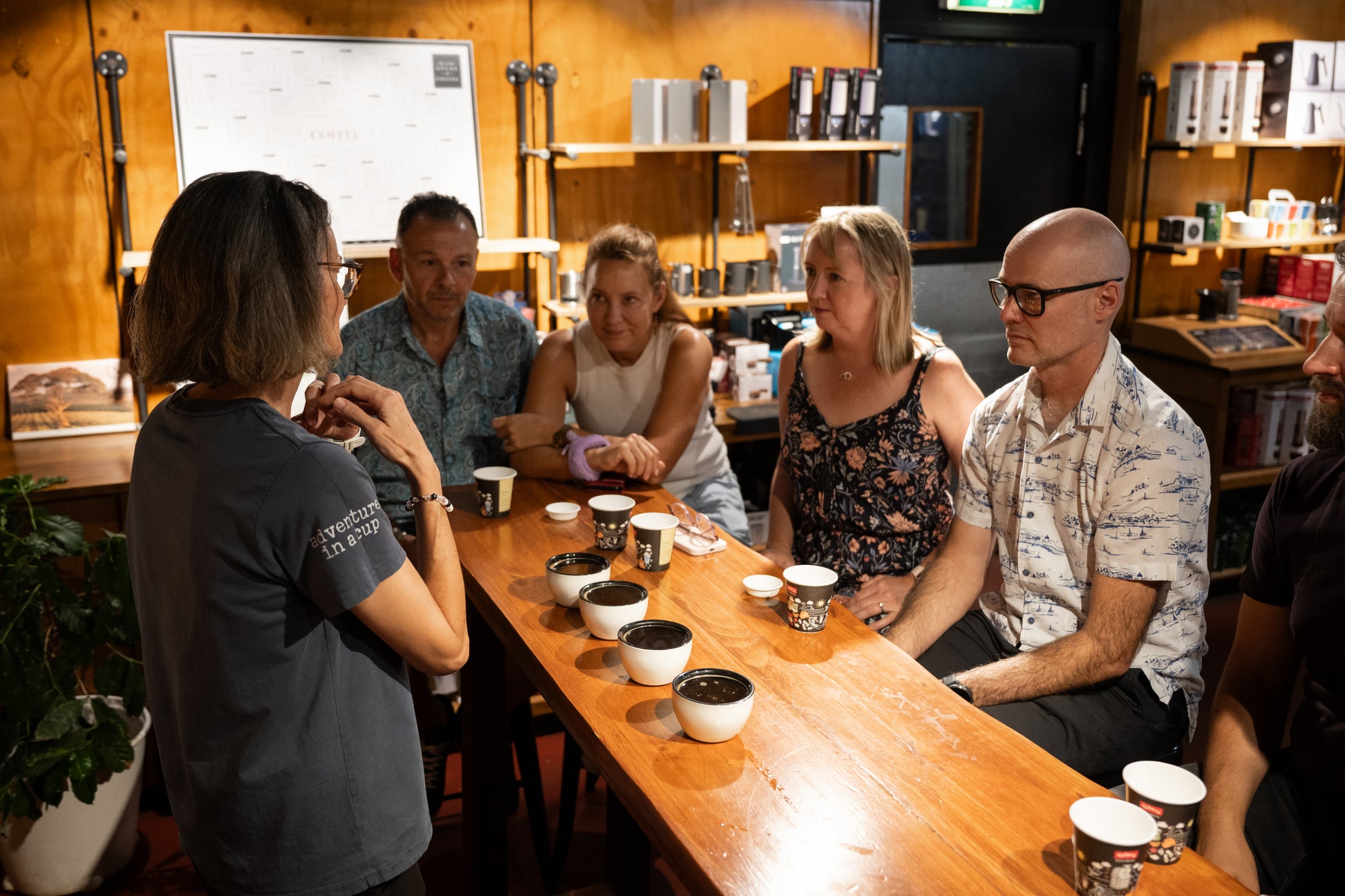 customers learning about coffee, how it is grown, roasted and how to drink. coffee cups and cupping bowls. 